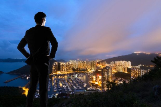 高台から夜景を見つめるスーツ姿の男性