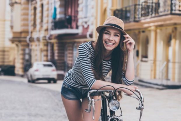 自転車にもたれかかり、こちらに笑顔を向ける髪の長い女性